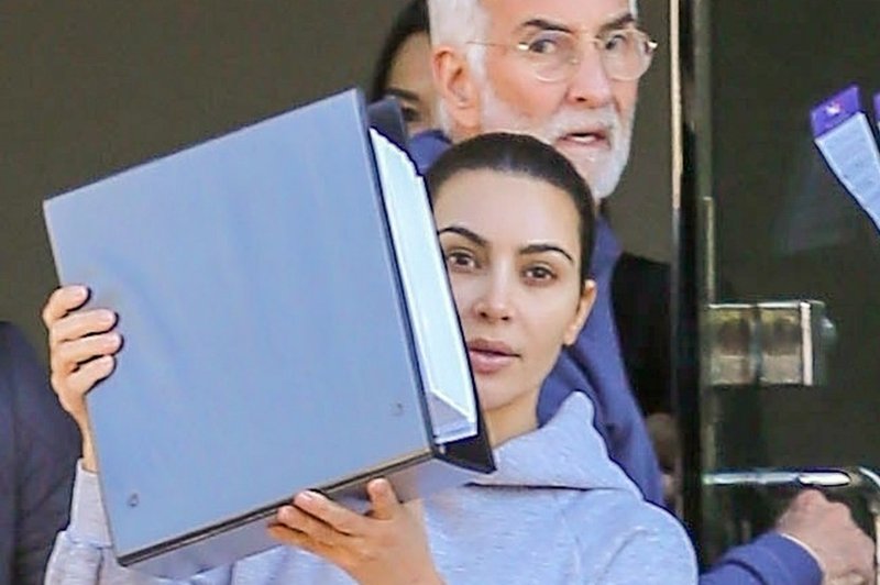 Kim Kardashian so paparaci ujeli povsem brez ličil, ko je hitela v avto in se skrivala za mapo (foto: Profimedia)