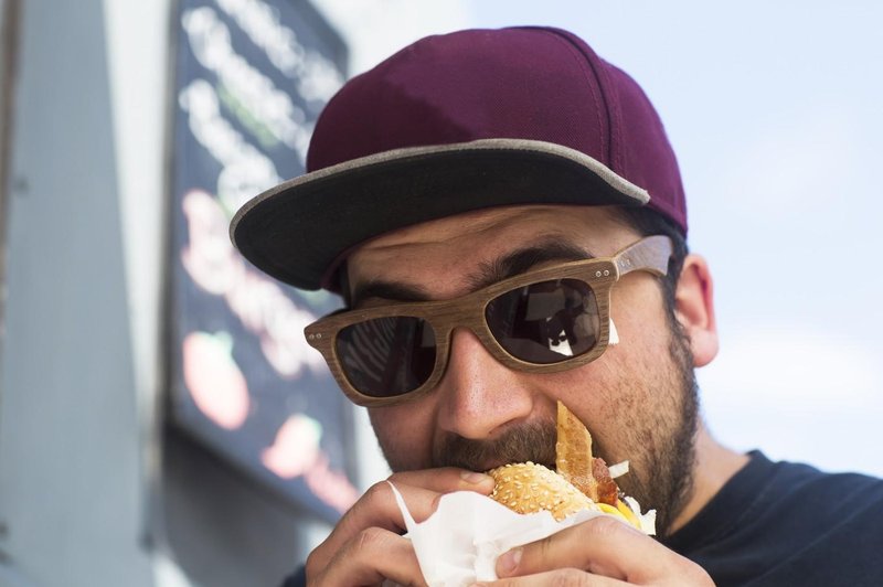 Moški med uživanjem v hamburgerju (foto: Profimedia)